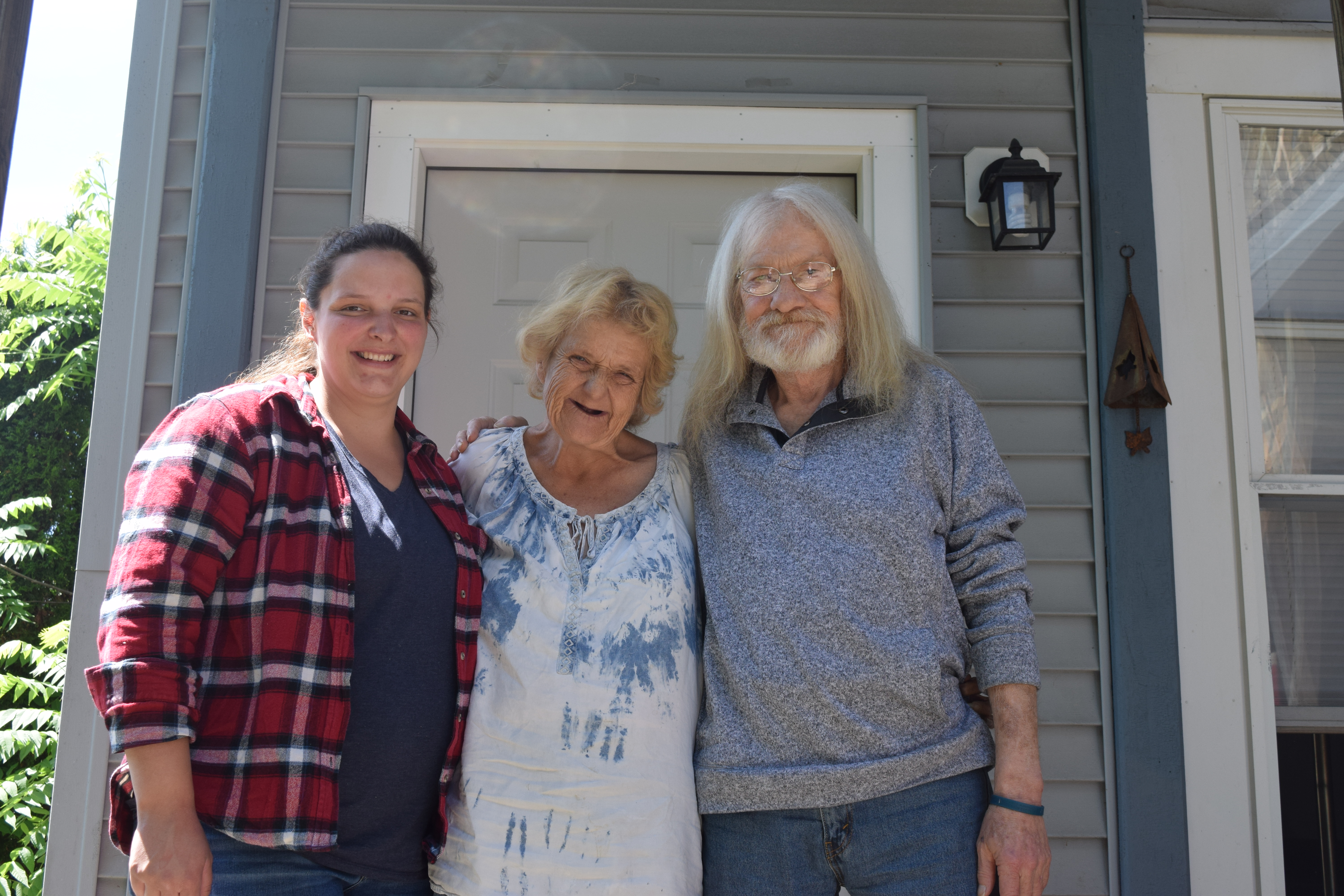 Three people standing together in front of a door.
