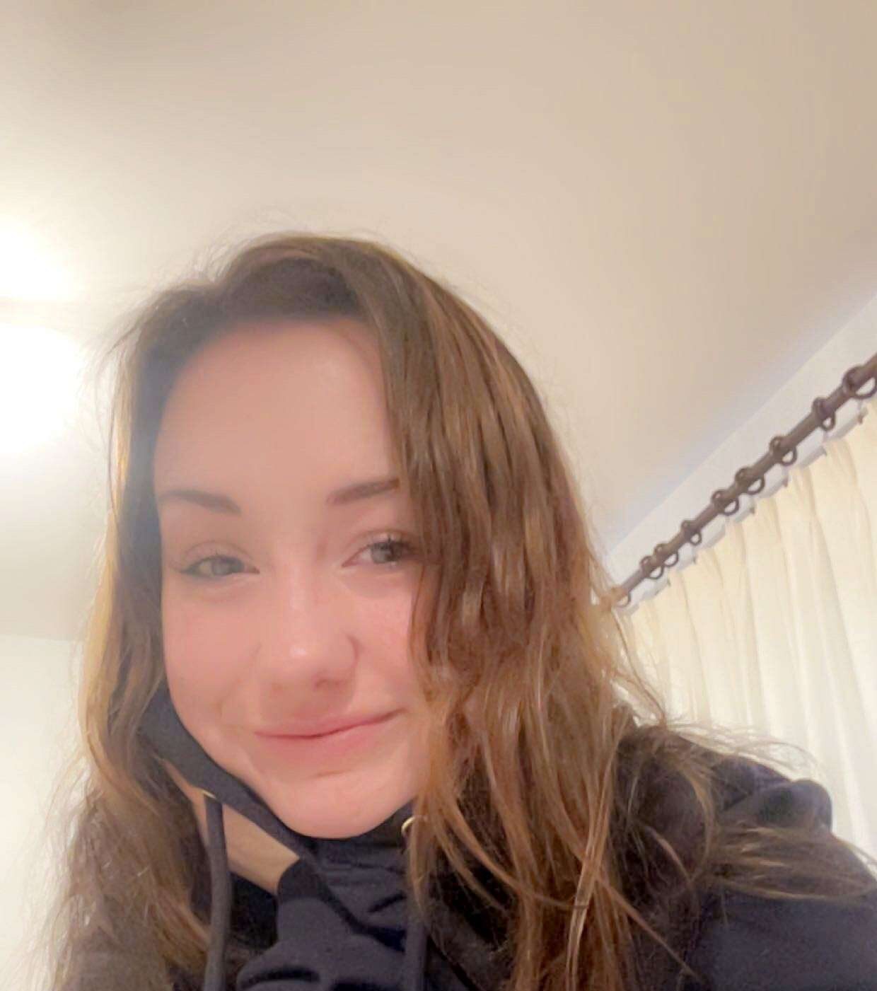 Selfie of a woman with long brown hair and a black hoodie